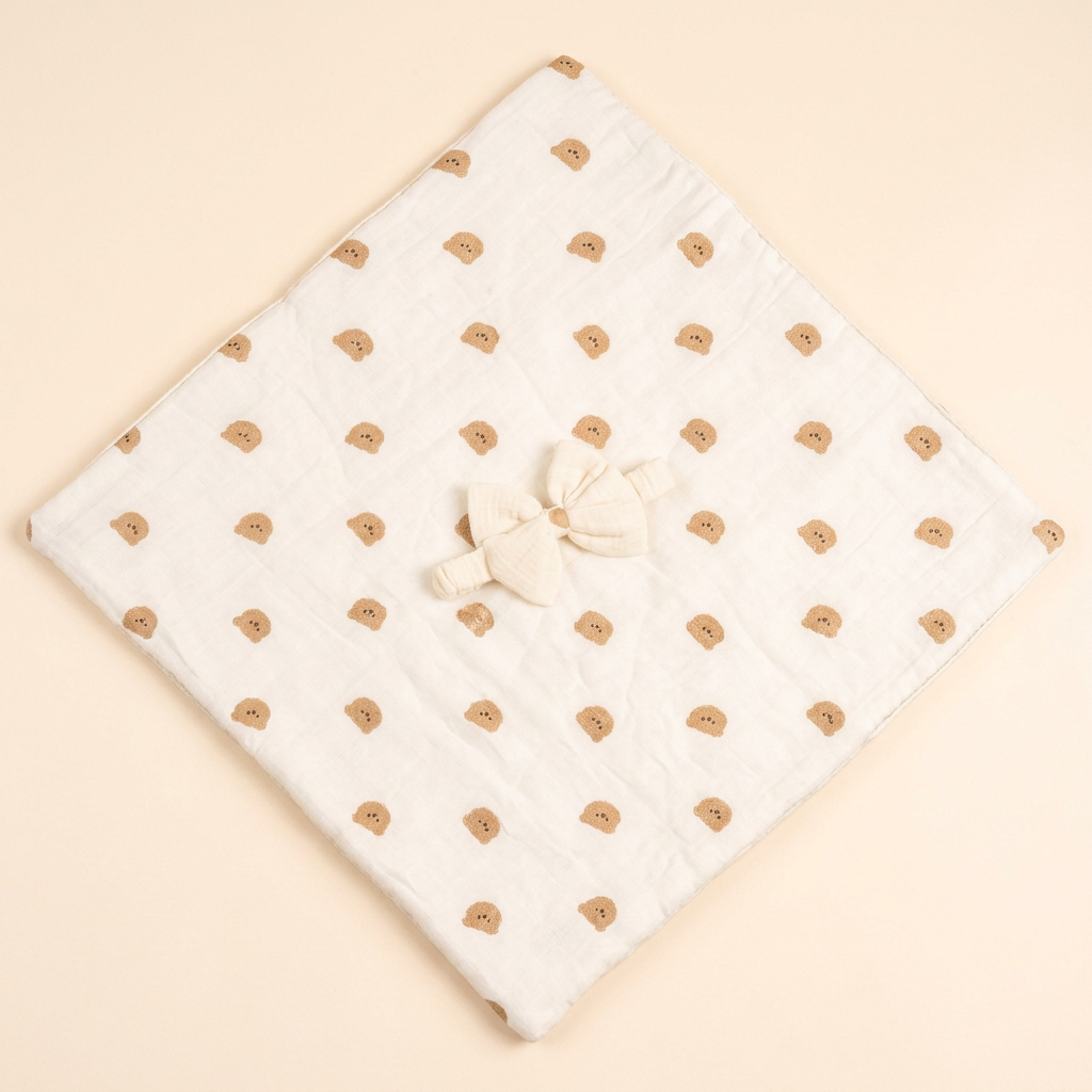 Off-white baby wrap opened out with tan teddy print and white bow detail